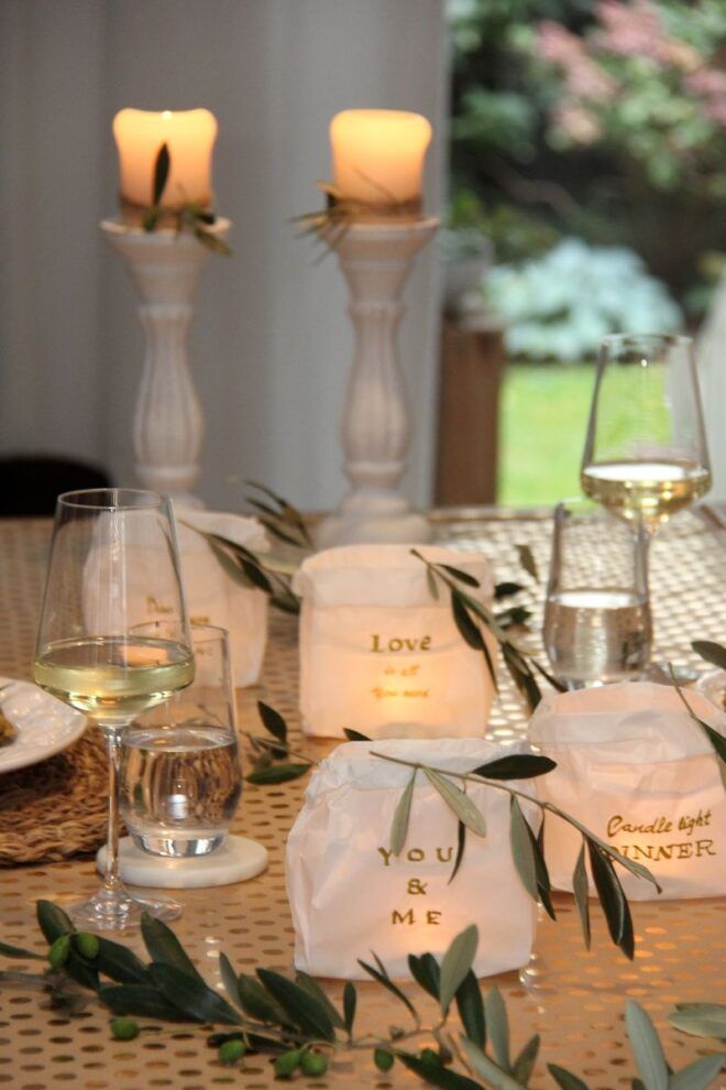 romantisch gedeckter Tisch mit Butterbrottüten, beschriftet und verziert mit Olivenzweigen