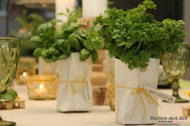 Kraeuter in leeren Milchtüten und gelbe Tischdeko frühlingshaft