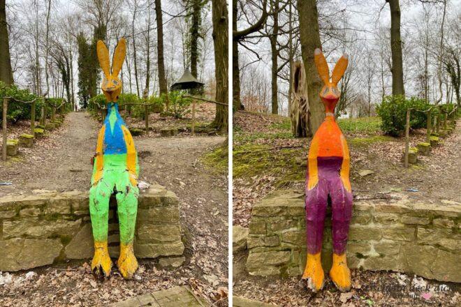 Große bunte Hasen aus Blech sitzen auf einem Stein im Wald