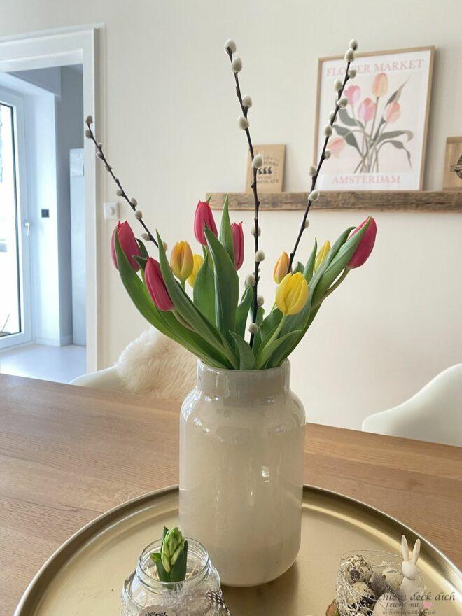 Tulpenstrauß mit weidenkätzchen in großer beiger Vase, Tulpen pink und gelb auf goldenem Tablett
