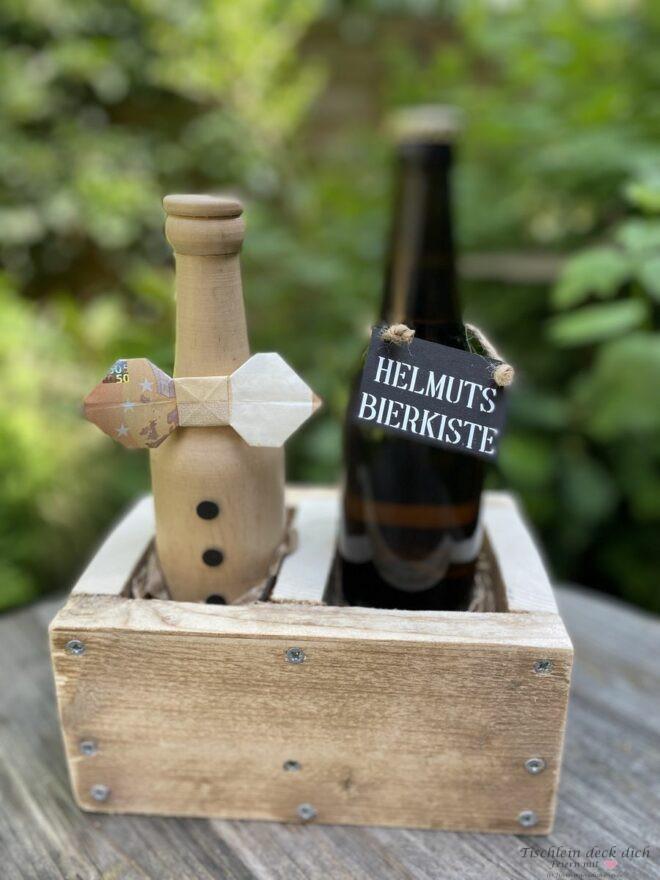 Geldgeschenk zum 60. Geburtstag in einer Holzkiste mit zwei Flaschen, eine Flasche aus Holz, eine aus Glas 