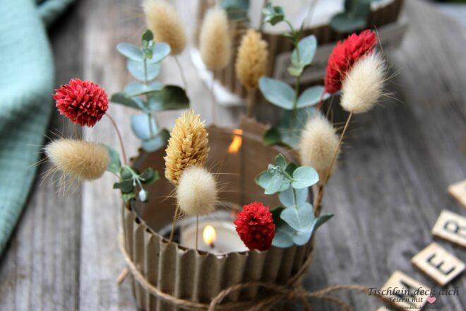 Schlichtes Windlichtglas mit Wellpappe und Trockenblumen verziert