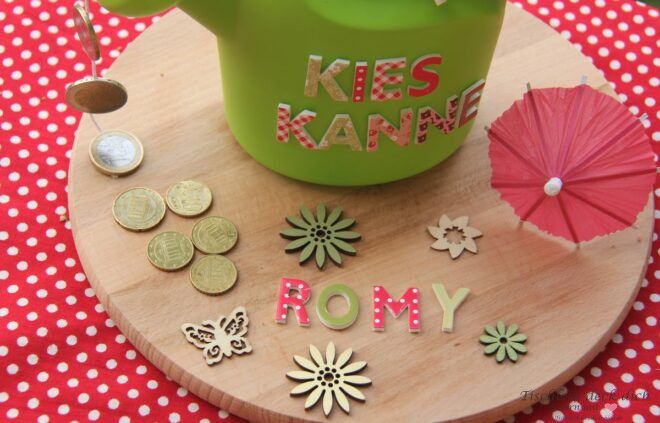 Geld verschenken mit Gießkanne auf einem Holztablett mit Streuartikeln und Münzen