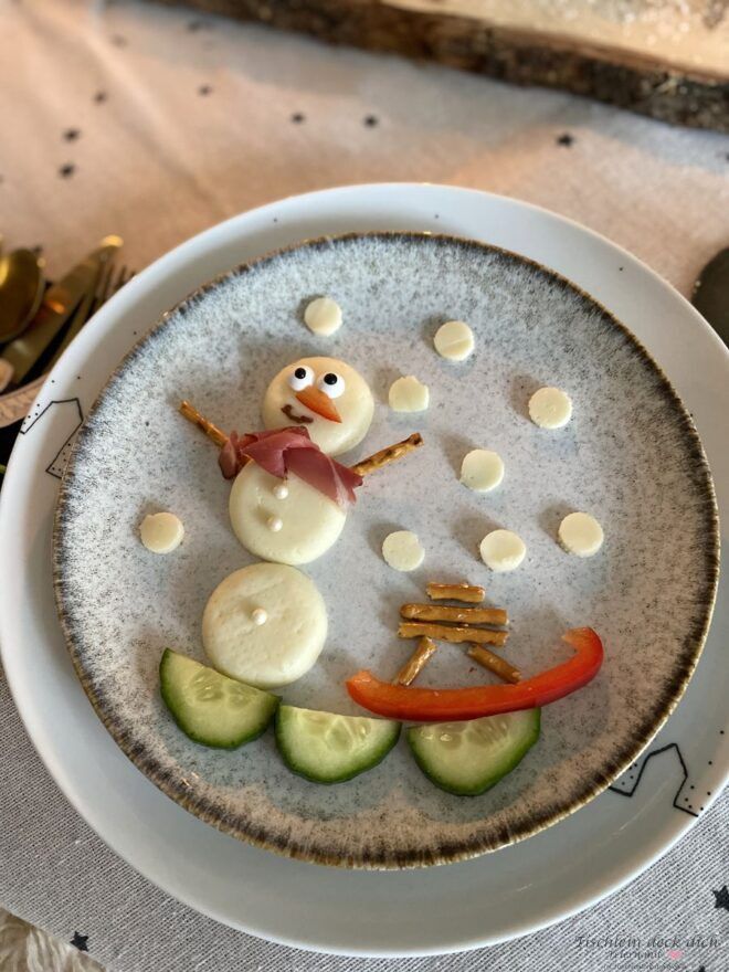Schneemann aus rundem Käse, dekoriert mit Paprika und Gurken, Fingerfood für Kinder