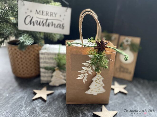 weihnachtliche Geschenkverpackung mit Tüte aus Packpapier und weiß goldenen Anhängern aus Modelliermasse