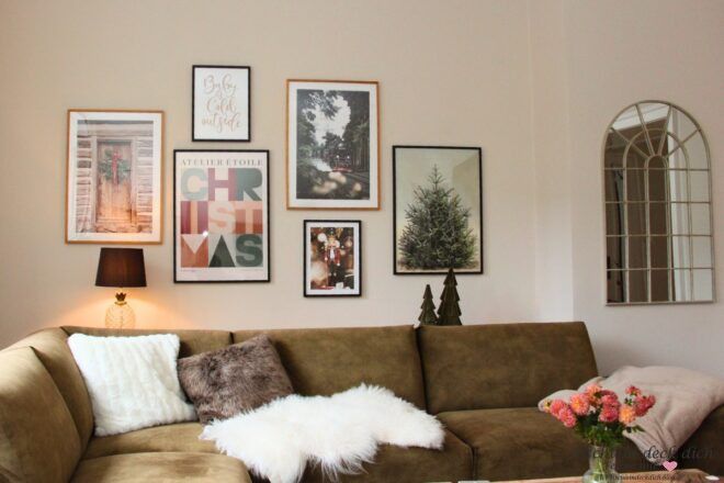 Wohnzimmer mit grünem Sofa und weihnachtlicher Wandgestaltung mit Postern im Rahmen
