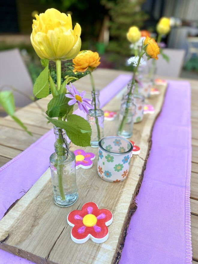 Tischdeko Sommer mit bunten Blumen auf Holzbrett dekoriert