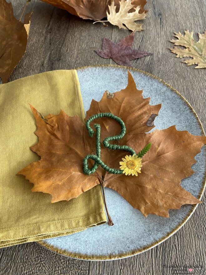 Buchstabe B aus Draht mit grüner Kordel auf großem Herbstblatt